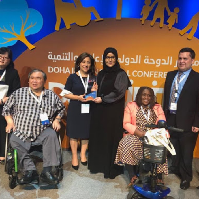 Fotografía oficial de un grupo de 6 personas en el escenario de la Conferencia Internacional de Doha sobre Discapacidad y Desarrollo, de entre quienes destacan Sebastian Flores (Co-Fundador de Fundación Comparlante) y Ana Lucía Arellano (Secretaria de la Alianza Internacional de Discapacidad.