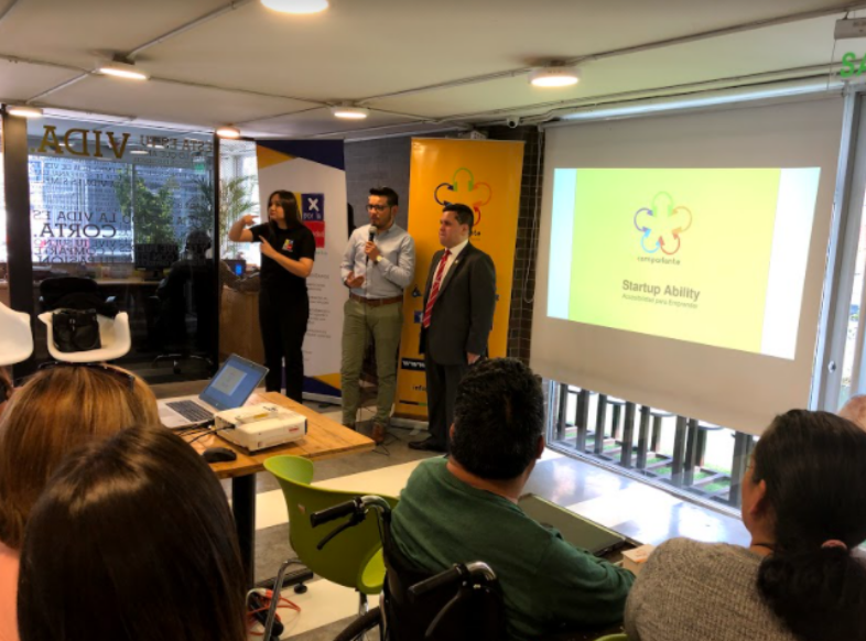 Roberto Jaramillo, Entrepreneurship Project Manager addresses the audience of the workshop for persons with disabilities at IMPAQTO. Standing beside him appear Sebastian Flores, Co-Founder of Fundación Comparlante and a Sign Language interpreter.