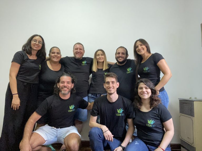 Photo of the team behind LSApp. All are smiling and wearing black t-shirts with the App logo.