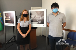 Fotografía de Lorena Julio (Presidente de Fundacion Comparlante) de pie junto a Carlos Morelli (Director de La Secretaria de Desarrollo de la Municipalidad de Villarino) junto a dos fotografías de la muestra Sentimos Villarino.