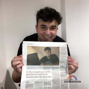 Gerónimo sonriendo a cámara sosteniendo la página que encabeza su nota en Diario Clarín. La hoja se titula “El chico elegido por la ONU para dar un mensaje al mundo sobre discapacidad”. Debajo, el logo de Fundación Comparlante.