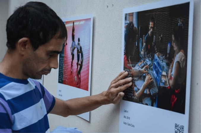 Lelio Sánchez, a blind persons, runs his hand over the Braille inscription that is above his photo at the opening of the Exhibition at MediHome, in the City of La Plata