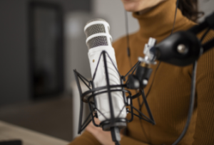 Una joven delante de un micrófono a punto de grabar un podcast en su sala de estar.